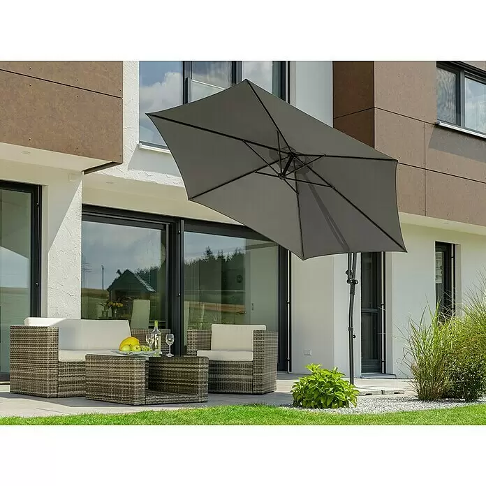 Schneider Sunny Ampelschirm rund Genua - Anthrazit, Durchmesser Bespannung: 300 cm - Eine graue Rattan-Sitzgruppe mit hellen Kissen auf einer modernen Terrasse, beschattet von einem großen dunkelgrauen Ampelschirm.