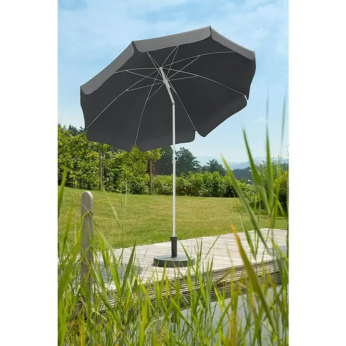 Schneider Classic Marktschirm rund IbizaAnthrazit, Durchmesser Bespannung: 240 cm - Ein grauer Sonnenschirm steht auf einer Holzterrasse, umgeben von üppigem Grün. Er bietet Schatten und Schutz vor der Sonne im Freien.