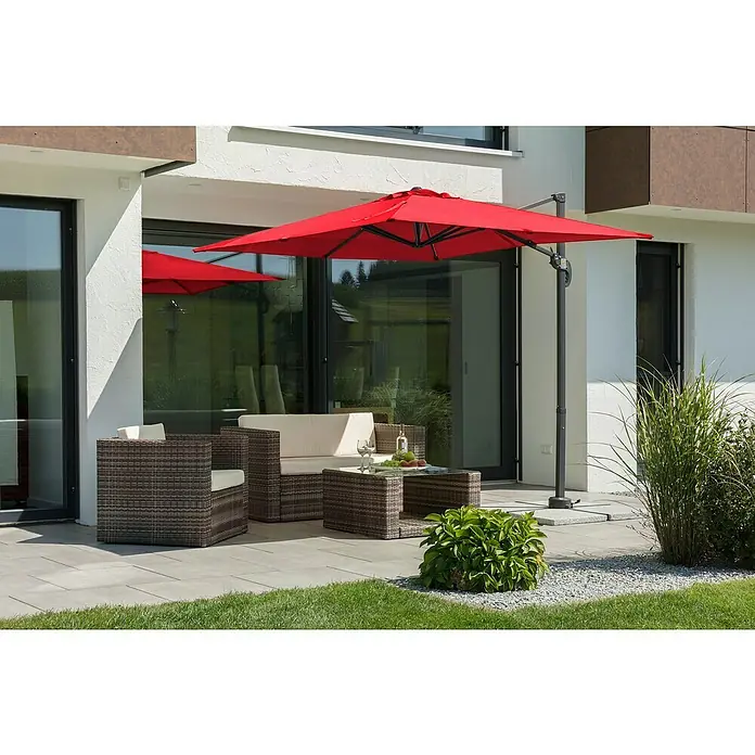 Schneider Classic Ampelschirm Rhodos Junior - Rot, Bespannungsmaß (L x B): 230 x 230 cm - Einladende Outdoor-Lounge mit rotem Sonnenschirm, Rattansesseln und Tisch auf einer gepflasterten Terrasse.