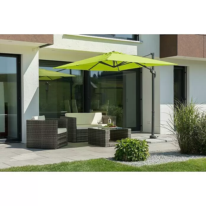 Schneider Classic Ampelschirm Rhodos Junior - Apfelgrün, Bespannungsmaß (L x B): 230 x 230 cm - Moderne graue Korbmöbel-Lounge-Gruppe mit cremefarbenen Kissen und einem großen limettengrünen Ampelschirm auf einer gepflasterten Terrasse.