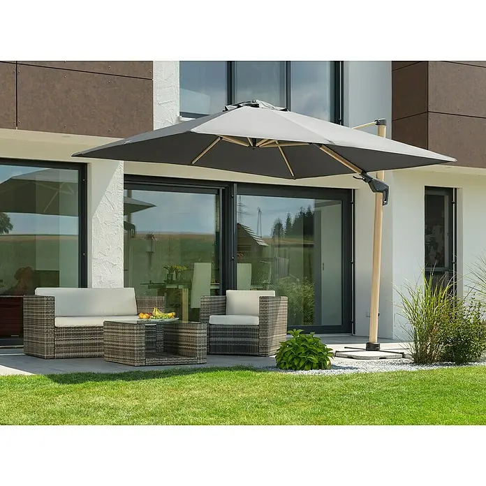 Schneider Classic Ampelschirm Rhodos Twist Woody - Anthrazit, Bespannungsmaß (L x B): 300 x 300 cm - Ein moderner grauer Sonnenschirm beschattet eine Terrassengarnitur mit Rattansesseln und Tisch auf einer grünen Rasenfläche.