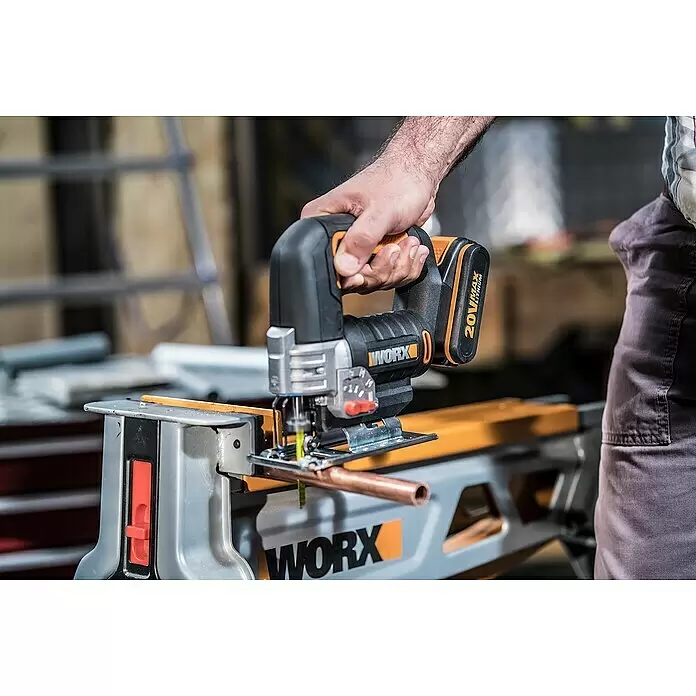 Worx PowerShare 20V Akku-Stichsäge WX543 - 20 V, 1 Akku, 2 Ah, Leerlaufhubzahl: 0 /min - 2.600 /min - Mann benutzt eine schwarz-orange WORX 20V Akku-Stichsäge, um ein Kupferrohr auf einer Werkbank zu schneiden.