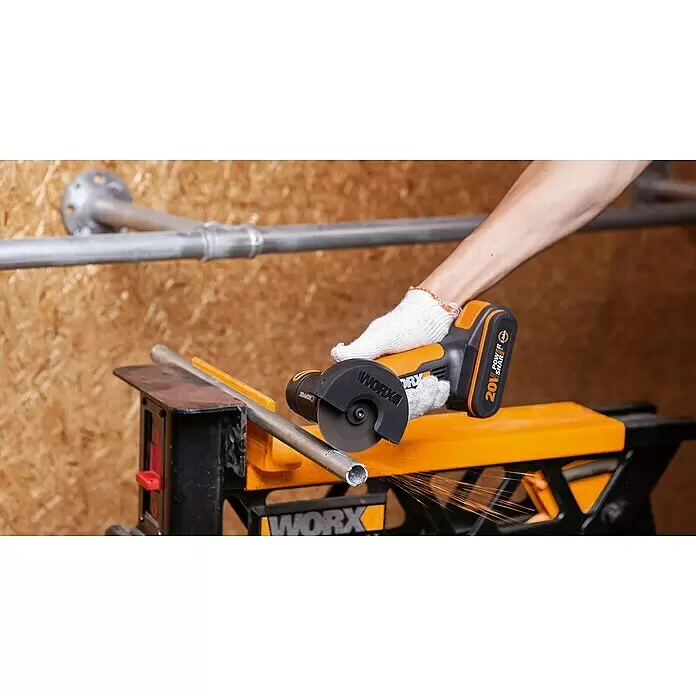 Worx PowerShare 20V Akku-Trennschleifer WX801 - 1 Akku, 2 Ah, Durchmesser Scheibe: 76 mm - Eine behandschuhte Hand verwendet einen schwarz-orangen WORX Akku-Winkelschleifer, um ein Metallrohr zu schneiden, wobei Funken entstehen.