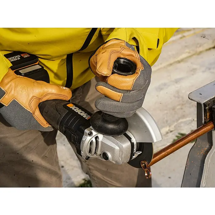 Worx PowerShare 20V Akku-Winkelschleifer WX812.9 - 20 V, Ohne Akku, Durchmesser Scheibe: 125 mm - Nahaufnahme einer Person, die mit einer Worx-Flex einen Kupferstab durchtrennt, wobei Schutzkleidung und Handschuhe getragen werden.