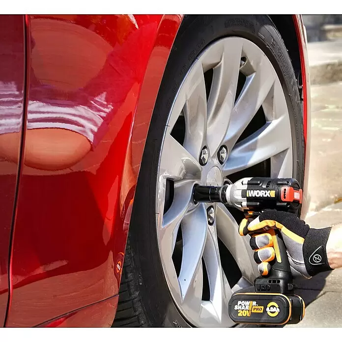 Worx PowerShare 20V Akku-Schlagschrauber WX272.9 - 20 V, Ohne Akku, 2 Ah, 300 Nm - Eine Person benutzt einen schwarzen und orangefarbenen WORX Schlagschrauber mit 20V Akku, um eine Radmutter von einem silbernen Rad eines roten Autos zu entfernen.