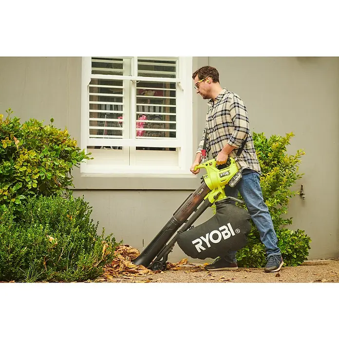 Ryobi ONE+HP Akku-Laubsauger & -Laubbläser RY18BVXA-150 - 1 Akku, 5 Ah, Blasleistung: 1,8 m³/min, Blasgeschwindigkeit: 252 km/h - Ein Mann benutzt einen RYOBI Laubbläser/Sauger, um Blätter aufzusaugen, mit Fenster und Grünpflanzen im Hintergrund.
