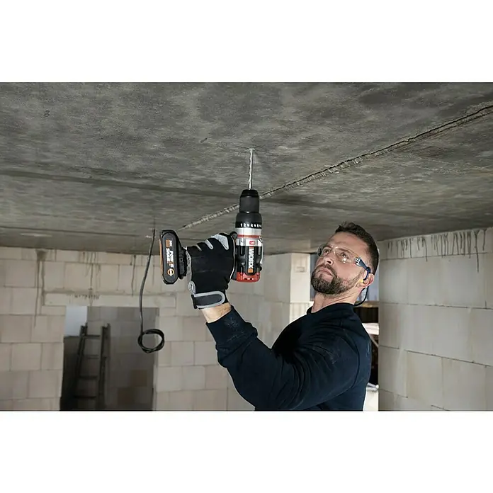 Worx PowerShare 20V Akku-Schlagbohrschrauber SlammerDrill WX354.9 - 20 V, Ohne Akku, Li-Ionen, 2 Ah, 60 Nm - Ein Mann bohrt mit einer WORX-Bohrmaschine ein Loch in eine Betondecke, wobei er Schutzbrille und Handschuhe trägt.