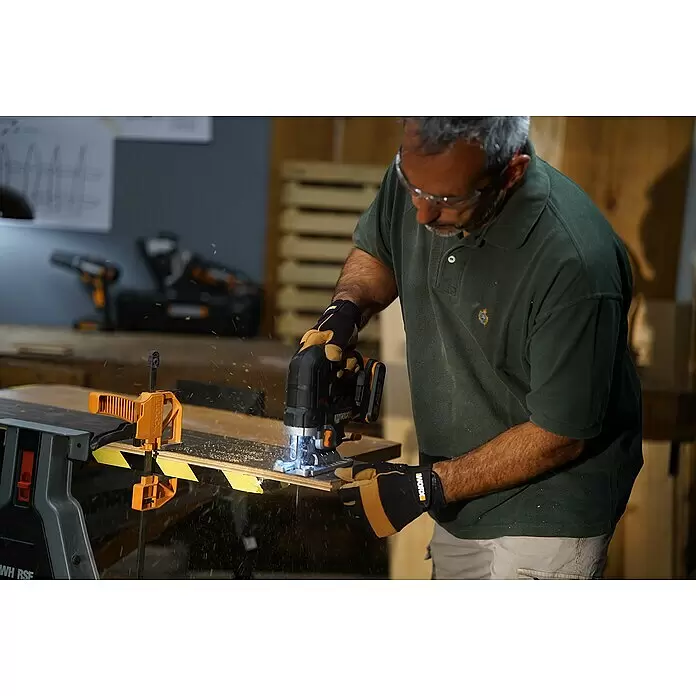 Worx PowerShare 20V Akku-Stichsäge WX542.9 - 20 V, Ohne Akku, Leerlaufhubzahl: 0 /min - 3.500 /min - Mann mit Schutzbrille und Handschuhen sägt Holz mit einer schwarz-orangen Akku-Stichsäge, Späne fliegen.