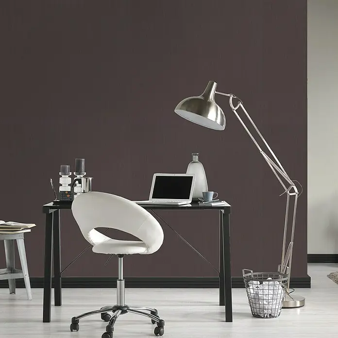 Vliestapete - Dunkelgrau, Uni, 10,05 x 0,53 m - Nahaufnahme eines modernen Arbeitsbereichs mit einem eleganten Schreibtisch, einem weißen Drehstuhl und einer Stehlampe.