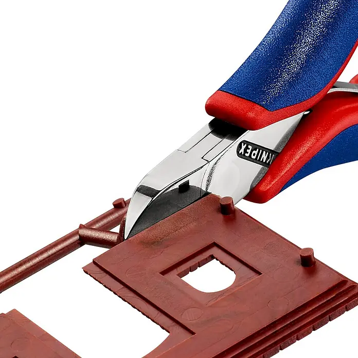 Knipex Seitenschneider - Länge: 11,5 cm, Härte Schneide: 60 HRC, Stahl - Nahaufnahme eines Knipex Seitenschneiders, der einen braunen Kunststoffrahmen durchtrennt, ideal für präzise Schnitte in Modellbau und Elektronik.