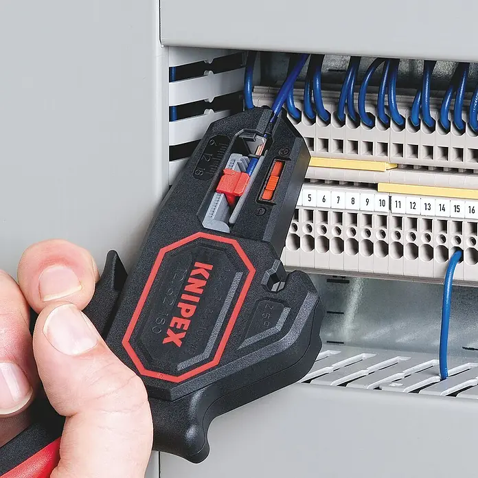 Knipex Abisolierzange - Länge: 18 cm - Nahaufnahme einer Knipex Abisolierzange 12 62 180 beim Abisolieren eines blauen Drahtes in einem Schaltschrank.