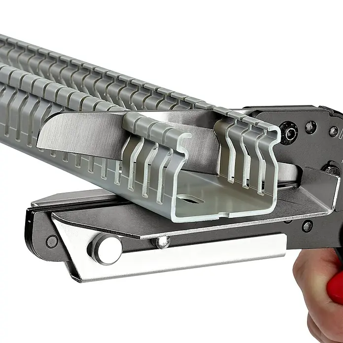 Knipex Schere - Geeignet für: Kunststoffprofile, Schnittlänge: 110 mm - Eine Werkzeugaufnahme mit grauem Kabelkanal, der geschnitten wird. Ideal für präzise Arbeiten im Elektrobereich.