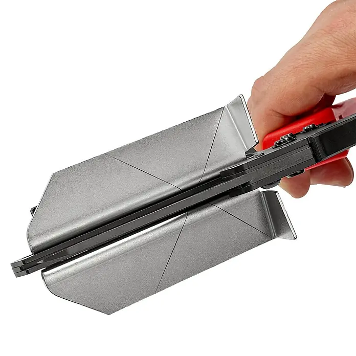 Knipex Schere - Geeignet für: Kunststoffprofile, Schnittlänge: 110 mm - Nahaufnahme einer manuellen Gehrungsschere mit rotem Griff und einer Hand, die sie bedient, vor einem schwarzen Hintergrund.