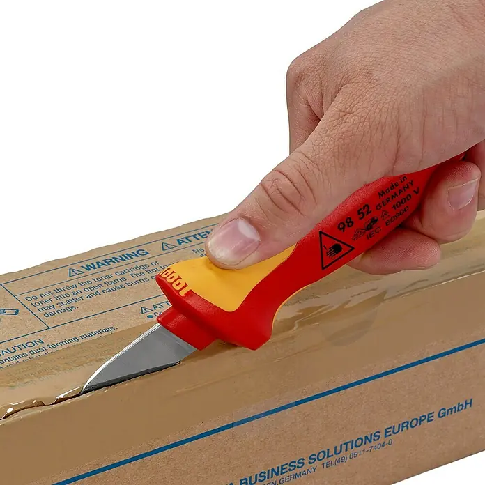 Knipex Kabelmesser - Schneide, Klingenlänge: 50 mm - Ein Elektrikermesser von Knipex mit rotem und gelbem Griff öffnet einen Karton.