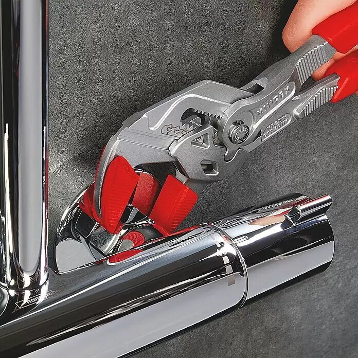 Knipex Wasserpumpenzange - Länge: 250 mm, Verchromt - Silberne Knipex Zangenschlüssel mit roten Griffen greifen ein glänzendes Chromrohr und zeigen ihren Einsatz bei Sanitärarbeiten.