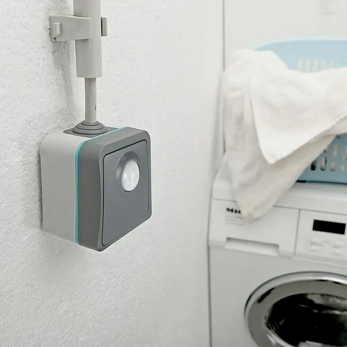 Voltomat Blueline Sensor-Schalter - Grau, Matt, 1-fach, Ausrichtung Schalterprogramm: Horizontal, Aufputzmontage, Schutzart: IP54 - Bild eines quadratischen Bewegungsmelders mit einem grauen Rahmen und einem blauen Akzentstreifen an einer weißen Wand.
