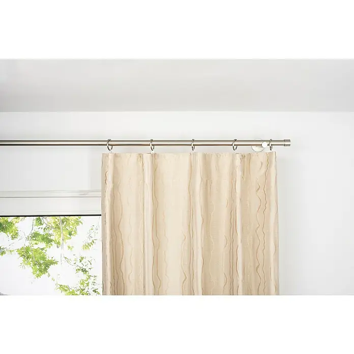 Schlaufenschal Stream - B x H: 135 x 300 cm, 100 % Polyester, Sand - Beige Gardine hängt an einer silbernen Gardinenstange vor einem Fenster und einer weißen Wand, die Textur des Stoffes ist elegant.