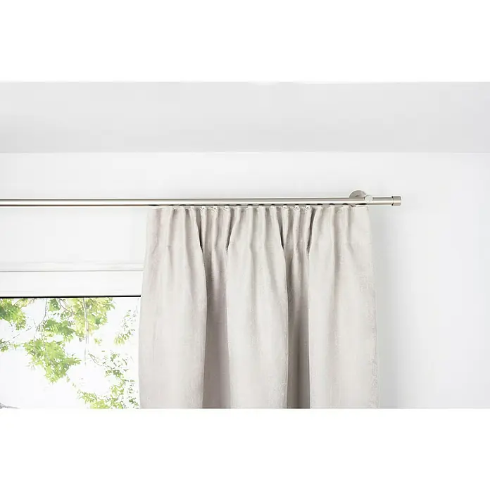 Verdunkelungsvorhang Dim - B x H: 135 x 300 cm, 100 % Polyester, Sand - Grauer Vorhang mit Faltenaufhängung an einer silbernen Gardinenstange vor einem Fenster und einer weißen Wand.