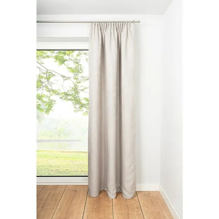 Verdunkelungsvorhang Dim - B x H: 135 x 300 cm, 100 % Polyester, Sand - Ein Vorhang aus beigem Stoff hängt vor einem Fenster und sorgt für ein angenehmes Ambiente im Raum. Die Textur des Vorhangs ist gut erkennbar.