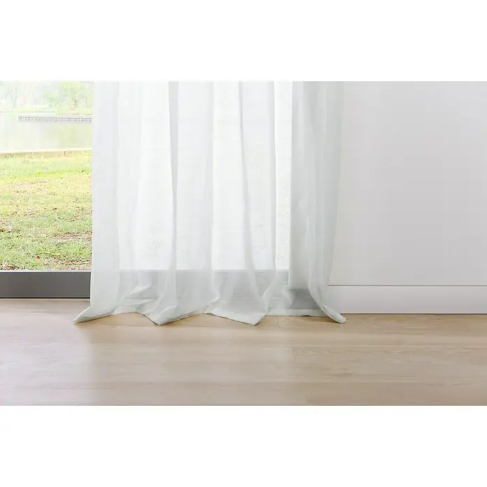 Ösenschal Transparent - B x H: 135 x 245 cm, 100 % Polyester, Weiß - Weißer, durchsichtiger Vorhang vor einem Fenster mit Blick auf eine grüne Landschaft, der einen Hauch von Eleganz in den Raum bringt.