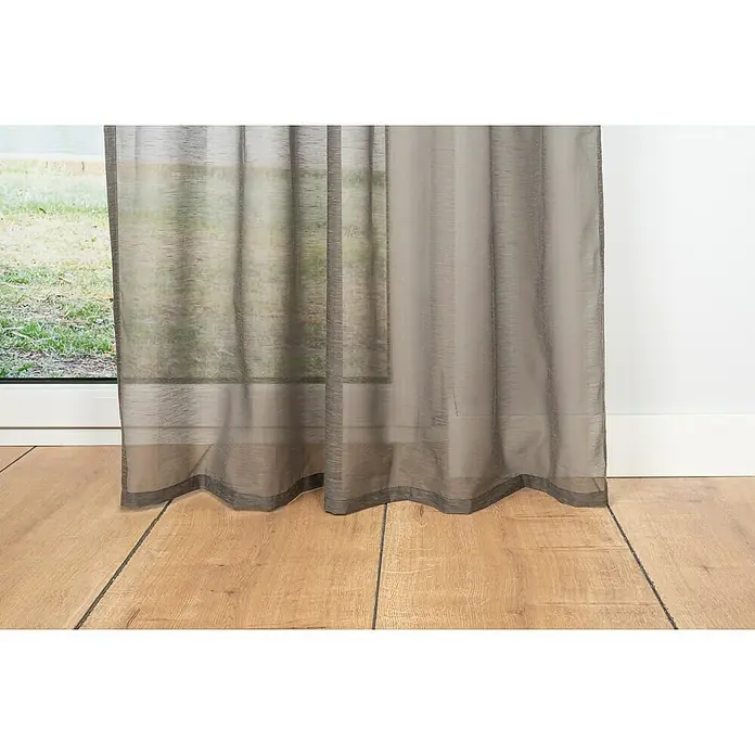Schlaufenschal Soft - B x H: 135 x 300 cm, 100 % Polyester, Taupe - Naheaufnahme von lichtdurchlässigen Gardinen, die vor einem Fenster und einer weißen Wand hängen, mit Holzboden im Vordergrund.