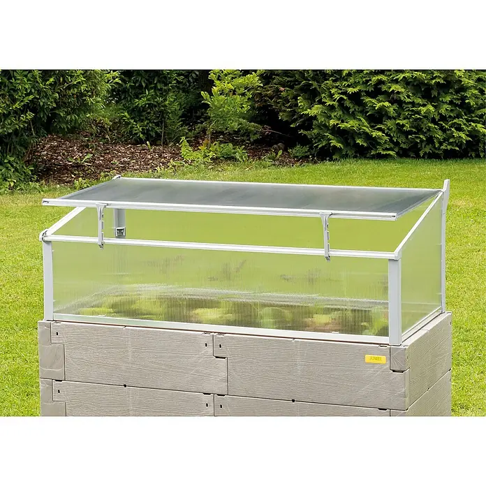 Juwel Frühbeet Thermo - 125 x 58 x 40 cm, Kunststoff - Nahaufnahme eines JUWEL Frühbeetaufsatzes auf einem Beetkasten im Garten, der mit einem transparenten Deckel und silbernen Rahmen ausgestattet ist.