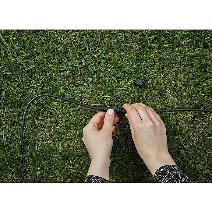 Garden 24 Verlängerungskabel - 5 m, Schwarz, IP44 - Hände verbinden zwei schwarze Stromkabelverbinder und montieren eine Stromleitung.