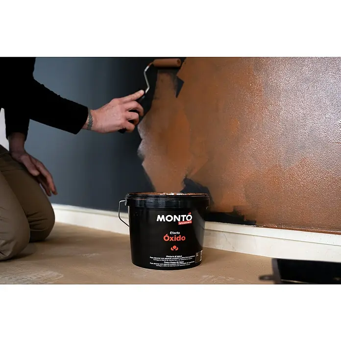 Montó Bricolovers Yeso con efecto de color - Óxido, 2,5 l, Mate - Un cubo negro de pintura Montó Efecto Óxido frente a una pared pintada a medias.
