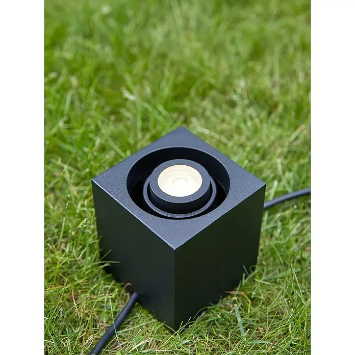 Garden 24 LED-Wegeleuchte - Schwarz, Höhe: 10,3 cm, Warmweiß - Moderne schwarze Gartenleuchte in Würfelform, eingebettet in grünes Gras. Sie strahlt ein warmes, einladendes Licht aus.