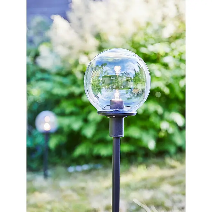 Garden 24 LED-Wegeleuchte - Schwarz, Höhe: 60 cm, Warmweiß - Eine moderne Gartenleuchte mit einer klaren Glaskugel auf einem schlanken, schwarzen Ständer, die eine sanfte Beleuchtung für den Außenbereich bietet.