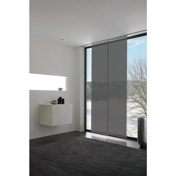 Expo Ambiente Flächenvorhang Pure - Grau, Kunststoff, B x H: 60 x 245 cm, Aufhängung: Klettband - Moderne graue Schiebegardinen vor einem Fenster in einem hellen Raum, die Privatsphäre bieten und gleichzeitig Licht hereinlassen.