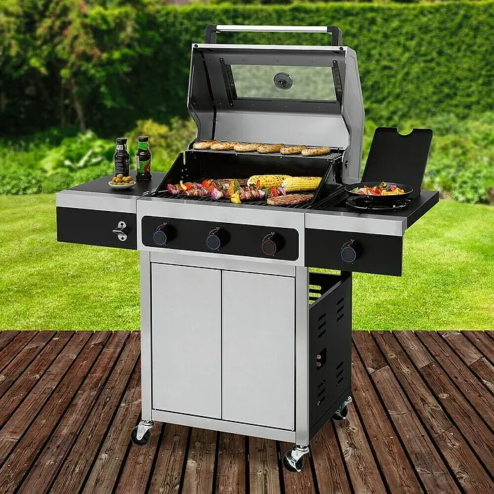 Tepro Gasgrill Keansburg Special Edition - Grillfläche (B x T): 61 x 43 cm, 10,6 kW, Anzahl Brenner: 3 - Ein Grill mit Speisen darauf steht auf einer Holzterrasse. Es gibt viel Zubehör und Schränke am Grill.