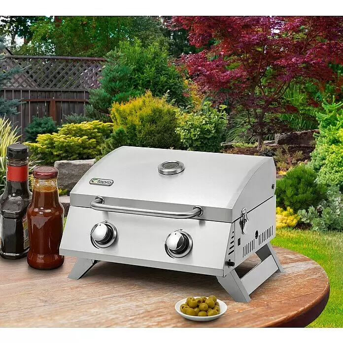 Tepro Gasgrill Chicago - Grillfläche (B x T): 47 x 36 cm, 6 kW, Anzahl Brenner: 2 - Tragbarer Edelstahl-Gasgrill mit zwei Knöpfen und Temperaturanzeige auf einem Holztisch im Garten.