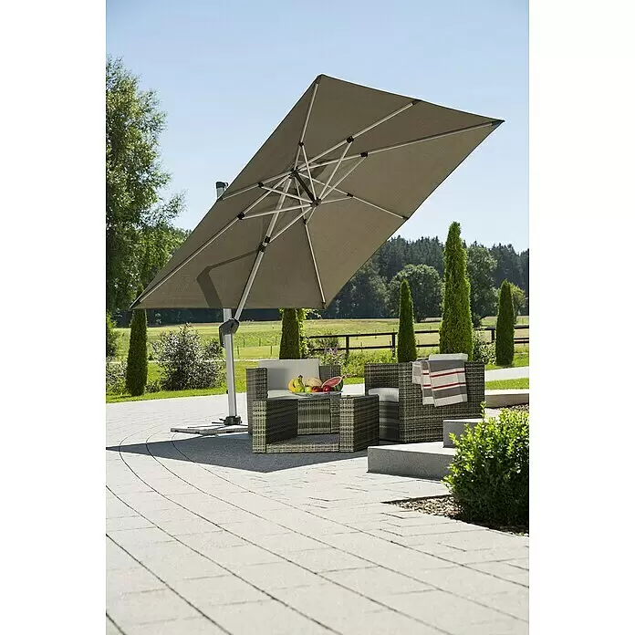 Schneider Premium Ampelschirm Monaco - Granitgrau, Bespannungsmaß (L x B): 300 x 300 cm - Großer taupefarbener Ampelschirm spendet Schatten über einer Outdoor-Sitzgruppe aus Polyrattan mit Obstschale auf einer gepflasterten Terrasse.