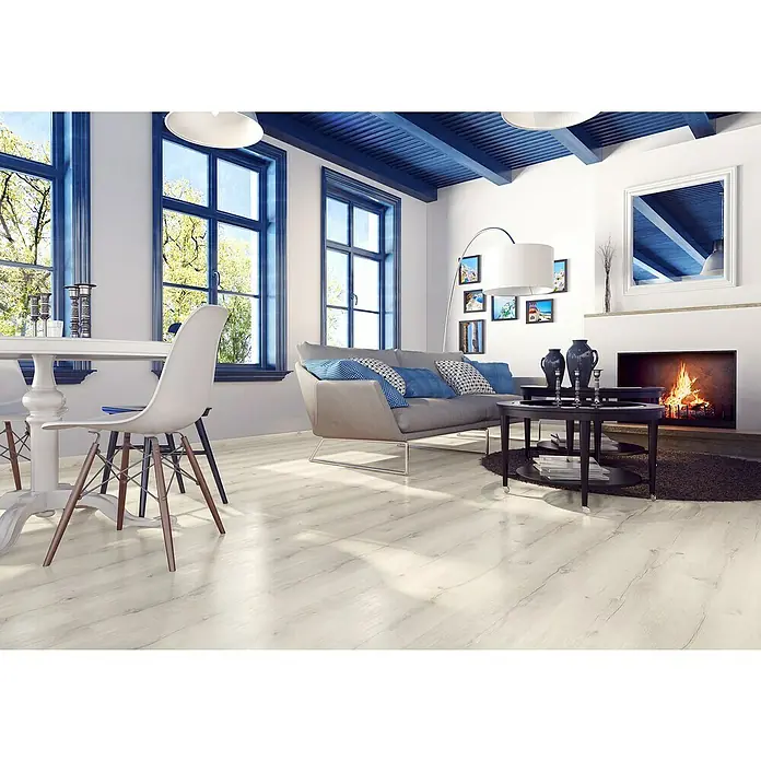 LOGOCLIC Junta de transición Madox - 2,44 m x 42 mm x 12 mm, Pegado - Un salón luminoso con suelos de madera blanca, marcos de ventanas azules y una chimenea. El suelo crea un ambiente acogedor.