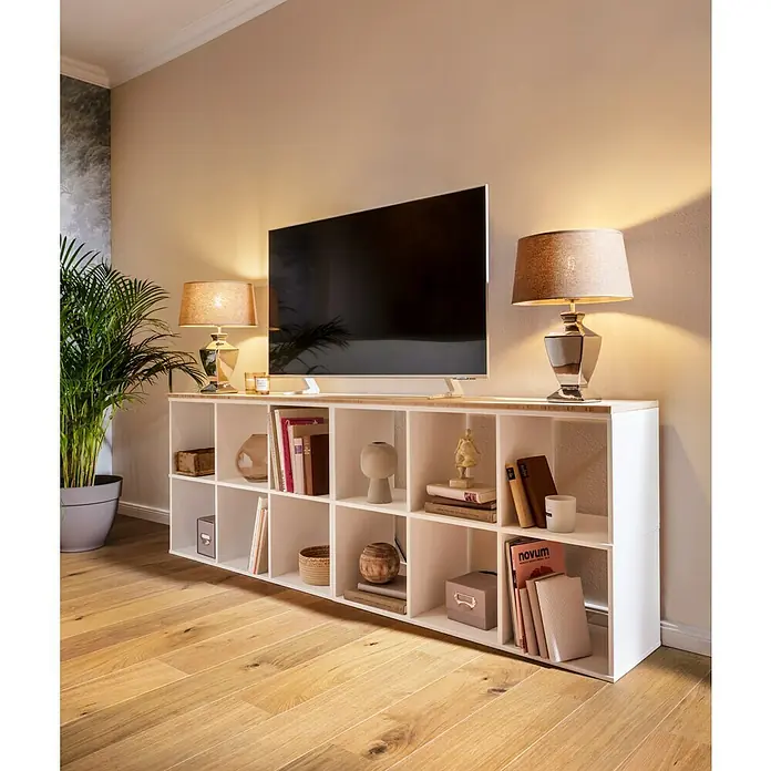 swingcolor Soft Colors Wandfarbe - Amber, Matt, 5 l - Ein modernes Wohnzimmer mit einem weißen, würfelförmigen Bücherregal, das als TV-Ständer dient und mit Dekoartikeln gefüllt ist.