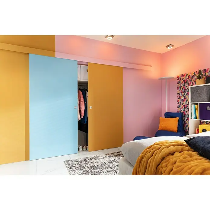 Optimum Schiebetür-Komplettset Optirail - 83 x 204 cm, Streichfähig, Wabe - Das Bild zeigt ein Schlafzimmer mit bunten Schiebetüren, die den Kleiderschrank verstecken. Die Farbgestaltung ist modern und lebhaft.