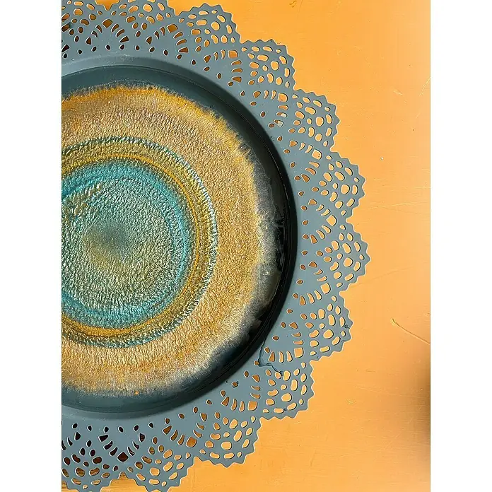Fleur Pigmento concentrado Polvo metálico - Azul, 5 g - Primer plano de una bandeja redonda decorativa con relleno de resina azul y dorada y un borde calado sobre una mesa naranja.