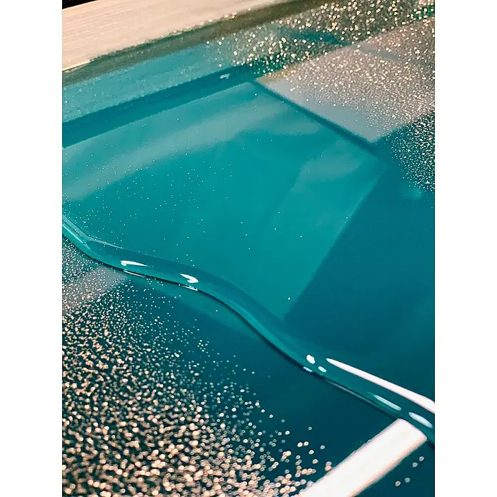 Fleur Purpurina Glitter - Champagne, 90 g, Brillante - Una intrigante toma abstracta que captura la superficie brillante de resina epoxi en un rico color teal, resaltada por reflejos de luz.
