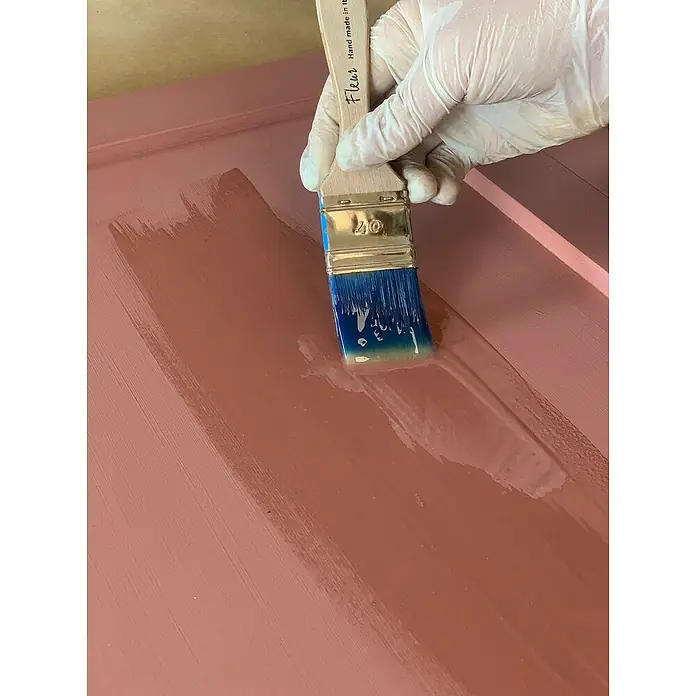 Fleur Resina epoxi Super Transparente - 950 ml, Transparente - Primer plano de un pincel de la marca Fleur aplicando pintura sobre una superficie rosa, ideal para proyectos de bricolaje y renovación del hogar.