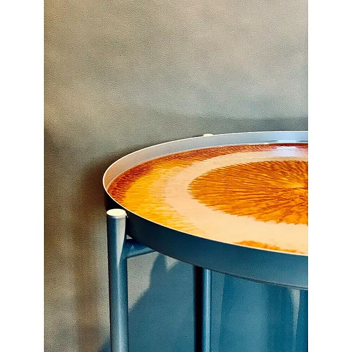 Fleur Resina epoxi Super Transparente - 480 ml, Transparente - Primer plano de una mesa auxiliar azul con una llamativa tapa redonda estampada en tonos naranja y blanco, con un toque moderno.