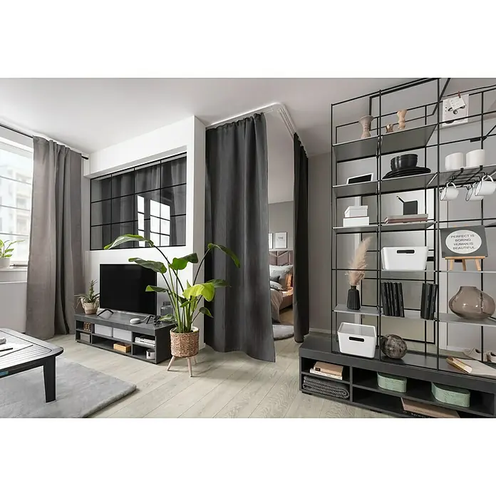 Elbersdrucke Verdunkelungsvorhang Midnight - 140 x 300 cm, 100 % Polyester, Grau - Wohnzimmer mit grauem Vorhang als Raumteiler, schwarzem Regal und TV-Möbel. Der Raum ist hell und modern eingerichtet.