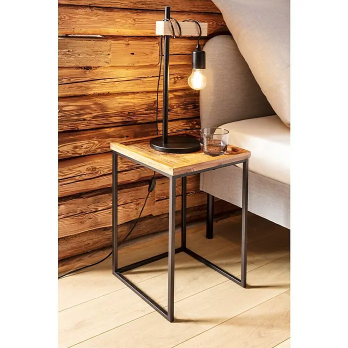 Beistelltisch - L x B x H: 33 x 33 x 52 cm, Mangoholz - Beistelltisch mit Holzplatte und Metallgestell neben einem Bett mit Lampe und Glas Wasser.