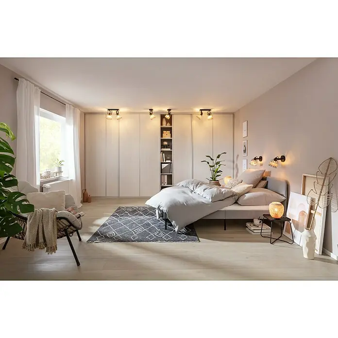 SCHÖNER WOHNEN-Farbe Wandfarbe Designfarbe - Weiches Strandbeige, Matt, 2,5 l, Konservierungsmittelfrei - Einladendes Schlafzimmer mit Kleiderschrankwand, großem Bett, Akzentteppich und stimmungsvoller Beleuchtung für eine gemütliche Atmosphäre.