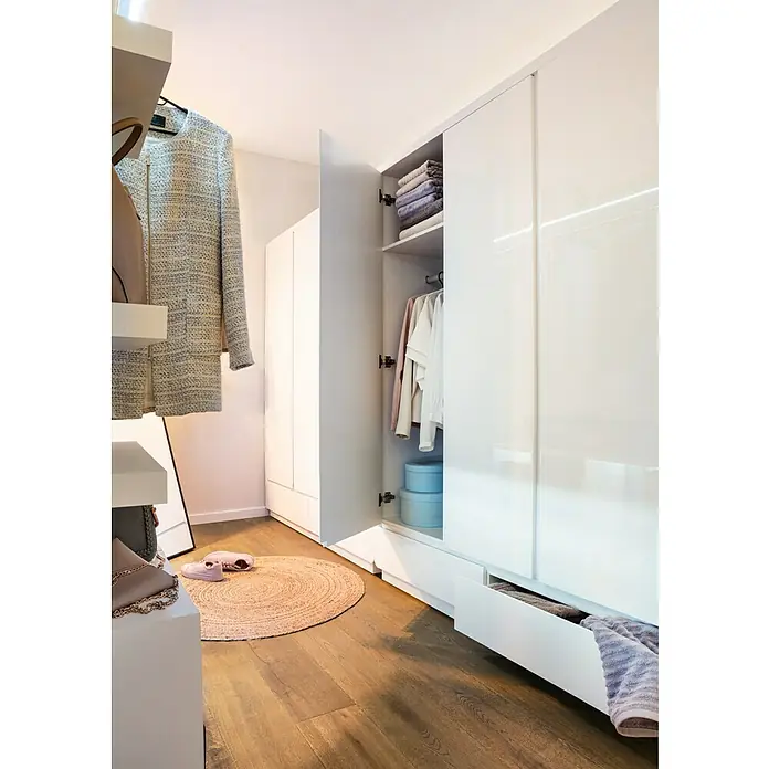 Juteteppich Jute - Natur, Durchmesser: 100 cm, 100% Jute - Offener, weißer Kleiderschrank mit Kleidung, Handtüchern und runden Boxen. Ein Teppich und Schuhe liegen davor auf dem Holzboden.