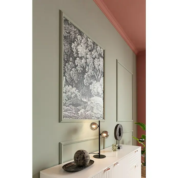 Nmc Decoflair Zierprofil Wandleiste CL1 - 2 m x 16 mm x 38 mm, Hochverdichtetes extrudiertes Polymer (HDPS) - Ein elegantes Interieur mit einem gerahmten Waldkunstdruck, einer modernen Lampe und dekorativen Elementen auf einem weißen Sideboard.