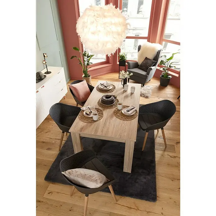 Fellteppich Happy - Graphit, 290 x 200 cm, 100 % Polyester (Flor) - Einladender Essbereich mit Holztisch, grauen Stühlen und flauschigem Teppich unter einer Federleuchte. Geschirr und Dekorationen zieren den Tisch.