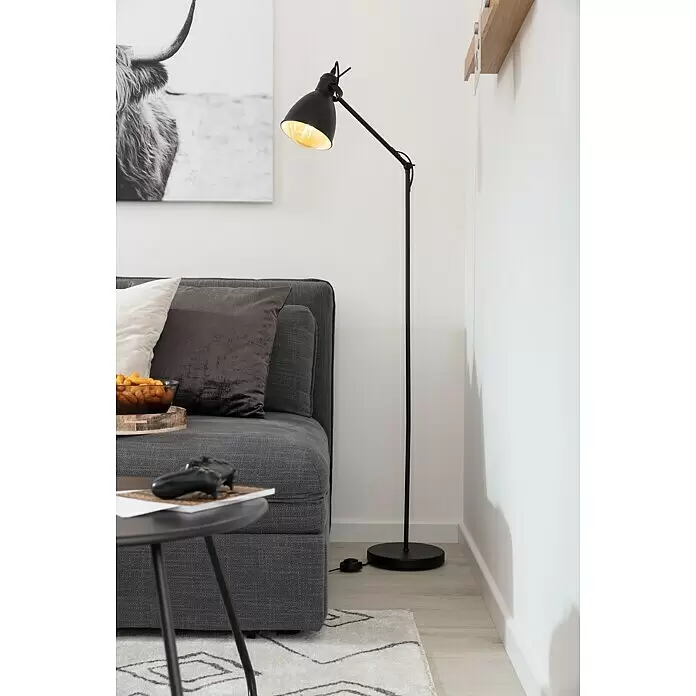 Eglo Priddy Stehleuchte Priddy - Höhe: 137 cm - Schwarze verstellbare Stehlampe mit sichtbarer Glühbirne, die neben einem grauen Sofa im Wohnzimmer stimmungsvolles Licht spendet.