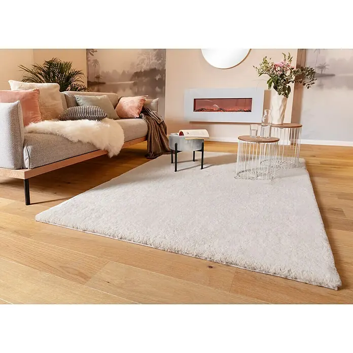 Fellteppich Happy - Elfenbein, 150 x 80 cm, 100 % Polyester (Flor) - Ein luxuriöser, flauschiger, rechteckiger, weißer Teppich liegt auf einem Holzboden und verleiht dem Raum Wärme und Eleganz.
