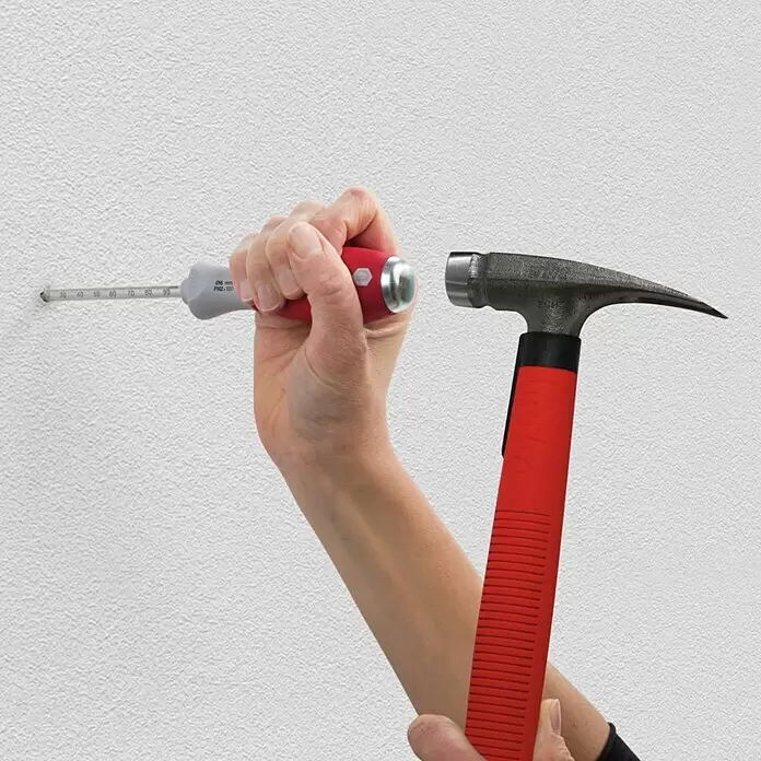 Wiha Dübellochschläger SoftFinish® - Geeignet für: Porenbeton, 5 -tlg. - Hand hält rote/graue Bohrtiefenlehre in Wand, bereit zum Einschlagen mit rotem/schwarzem Hammer.